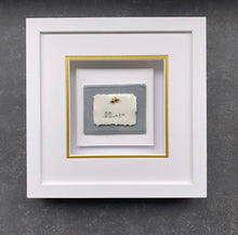 Load image into Gallery viewer, All You Need Is Love handmade porcelain wall piece in a white box frame with a bird-on-a-wire motif, hearts, and gold lustre detailsβon a soft grey toned tile.