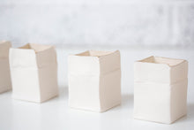 Load image into Gallery viewer, White handmade porcelain Boxeen tealight holders with softly irregular square forms and gold lustre rims, photographed in a bright minimal setting.