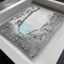 Load image into Gallery viewer, Angled view of Written in the Stars framed porcelain wall piece with textured grey edges and a soft turquoise centre with a starry sky and a gold north star